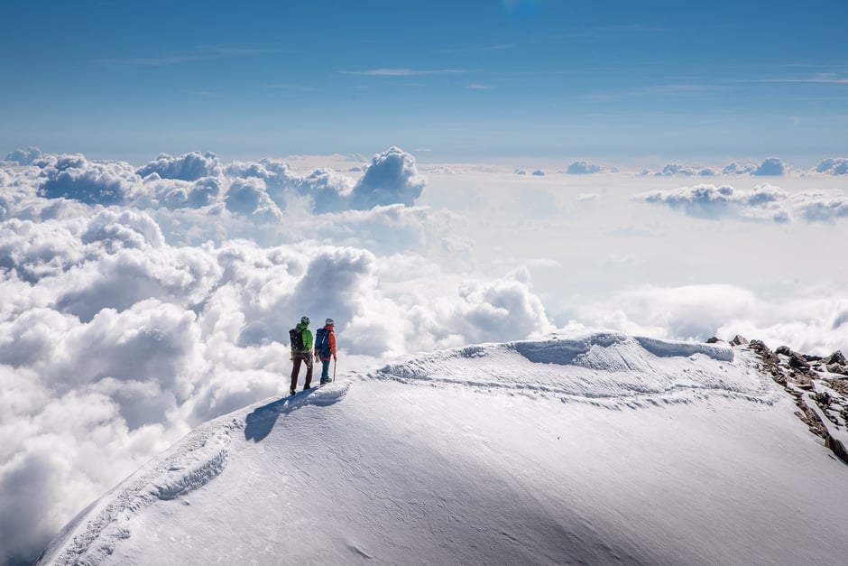 Nature image of two people on top of a snow covered mountain.
