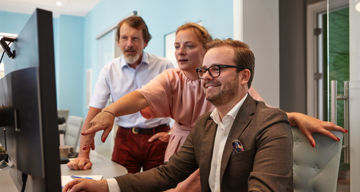 Picture of 3 people in a office in front of a pc screen